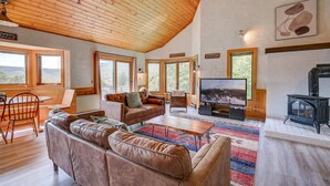 Ein gemütliches Wohnzimmer mit Holzboden, Ledersofas, einem Fernseher und einem Kamin.