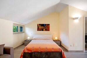 A bedroom with a bed, two bedside tables, a nightstand, a window, and a wall-mounted light fixture.