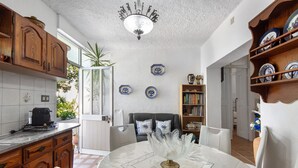 Una cucina con mobili in legno, un tavolo da pranzo con tovaglia bianca e un lampadario.