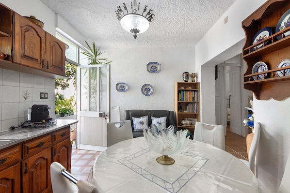 A kitchen with wooden cabinets, a dining table with a white tablecloth, and a ceiling light fixture.