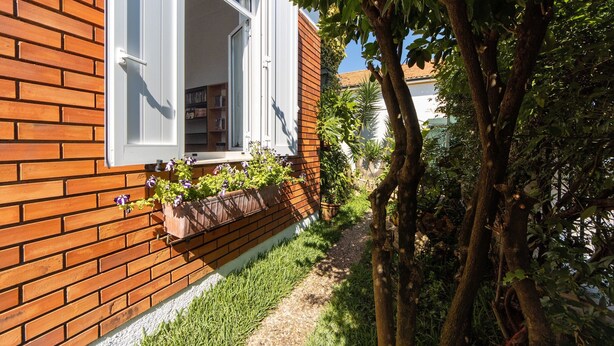Una casa in mattoni con una finestra, un vialetto e un albero.