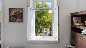 Una stanza con una finestra aperta, una libreria e un quadro appeso al muro.