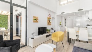 Un soggiorno moderno con TV, divano, zona pranzo e cucina.