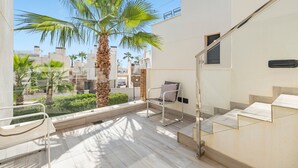 Un balcone con una palma, una sedia e una scala.
