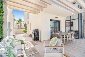 Un patio exterior con sofá, mesa y zona de barbacoa.