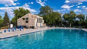 A swimming pool with lounge chairs and a building with a balcony. - Charming Arvada Home, Community Pool Jun-Aug (Arvada)