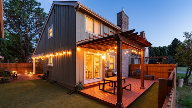 A two-story house with a deck, outdoor seating, and string lights. - Charming Arvada Home, Community Pool Jun-Aug (Arvada)