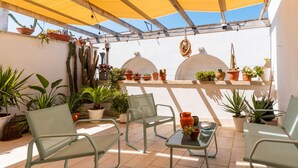 A covered patio with metal chairs, potted plants, and a table.
