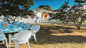 An outdoor dining area with a table set for four, surrounded by white chairs, under trees. - Chalet 'Villa Con Piscina Privada' with Private Pool, Private Terrace and Wi-Fi (Mas Vilet dels Pins)