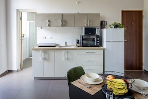 Una cucina moderna con mobili bianchi, un forno a microonde, una macchina da caffè e un frigorifero.