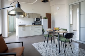 Una cucina moderna con mobili bianchi, un tavolo da pranzo con sedie e una lampada a sospensione.