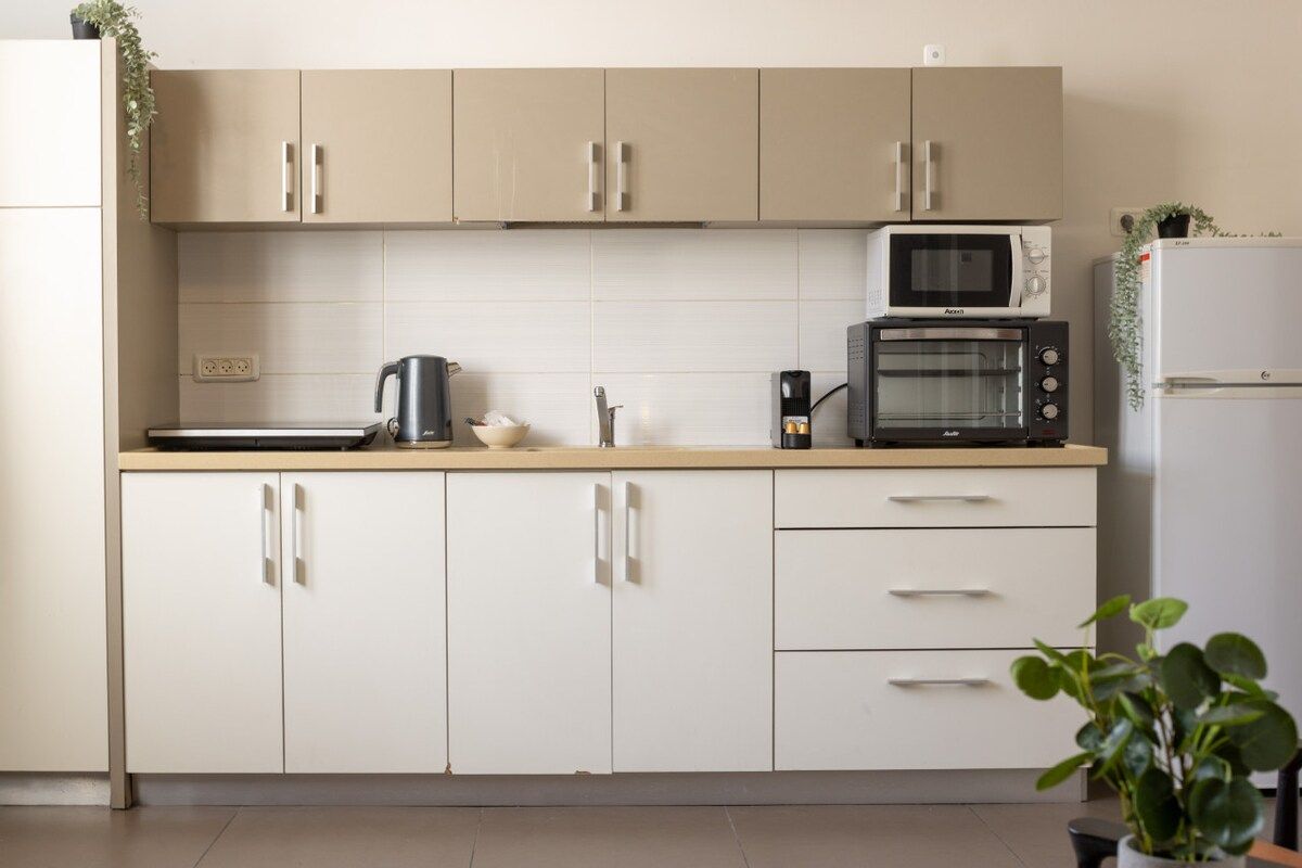 A kitchen with beige cabinets, a microwave, a toaster, and a refrigerator.