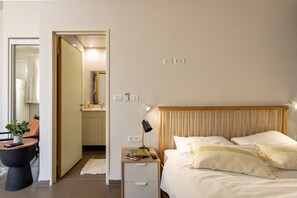 A bedroom with a bed, bedside table, lamp, and a small nightstand.