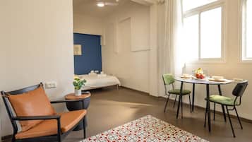 Ein Hotelzimmer mit einem Bett, einem kleinen Tisch mit Stühlen, einem Fenster mit Vorhängen und einem Deckenventilator.