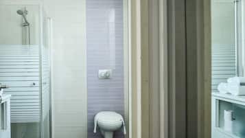 Un bagno con il WC, una doccia e uno spazio doccia con pareti in vetro.