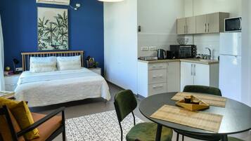Una habitación de hotel compacta con cama, una mesa de comedor y kitchenette.
