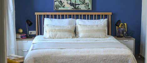 A bedroom with a bed, a nightstand, a lamp, and a wall art piece.