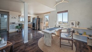 Een ruime zithoek met een marmeren salontafel, houten stoelen en uitzicht op de stad.
