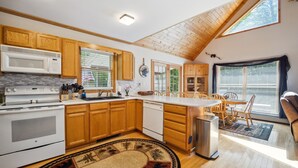Una cocina moderna con armarios de madera, una isla central y un comedor con mesa y sillas.