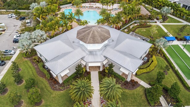 Vista aérea de un complejo turístico con una piscina central, palmeras y un edificio grande con una estructura de techo distintiva.