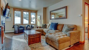 A living room with a sectional sofa, a coffee table, and a TV mounted on the wall. - WP Resort Ski In Out Condo 2403 I Hot Tub I Gym I Ski Views I Bunk Room I Discounted Attractions (Winter Park)