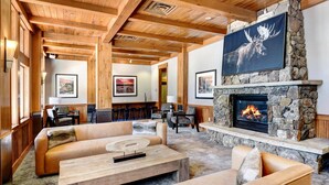 A cozy lounge area with a stone fireplace, wooden ceiling beams, and comfortable seating. - WP Resort Ski In Out Condo 2403 I Hot Tub I Gym I Ski Views I Bunk Room I Discounted Attractions (Winter Park)