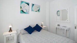 A bedroom with a bed, two nightstands, a dresser, a mirror, and two wall-mounted paintings.