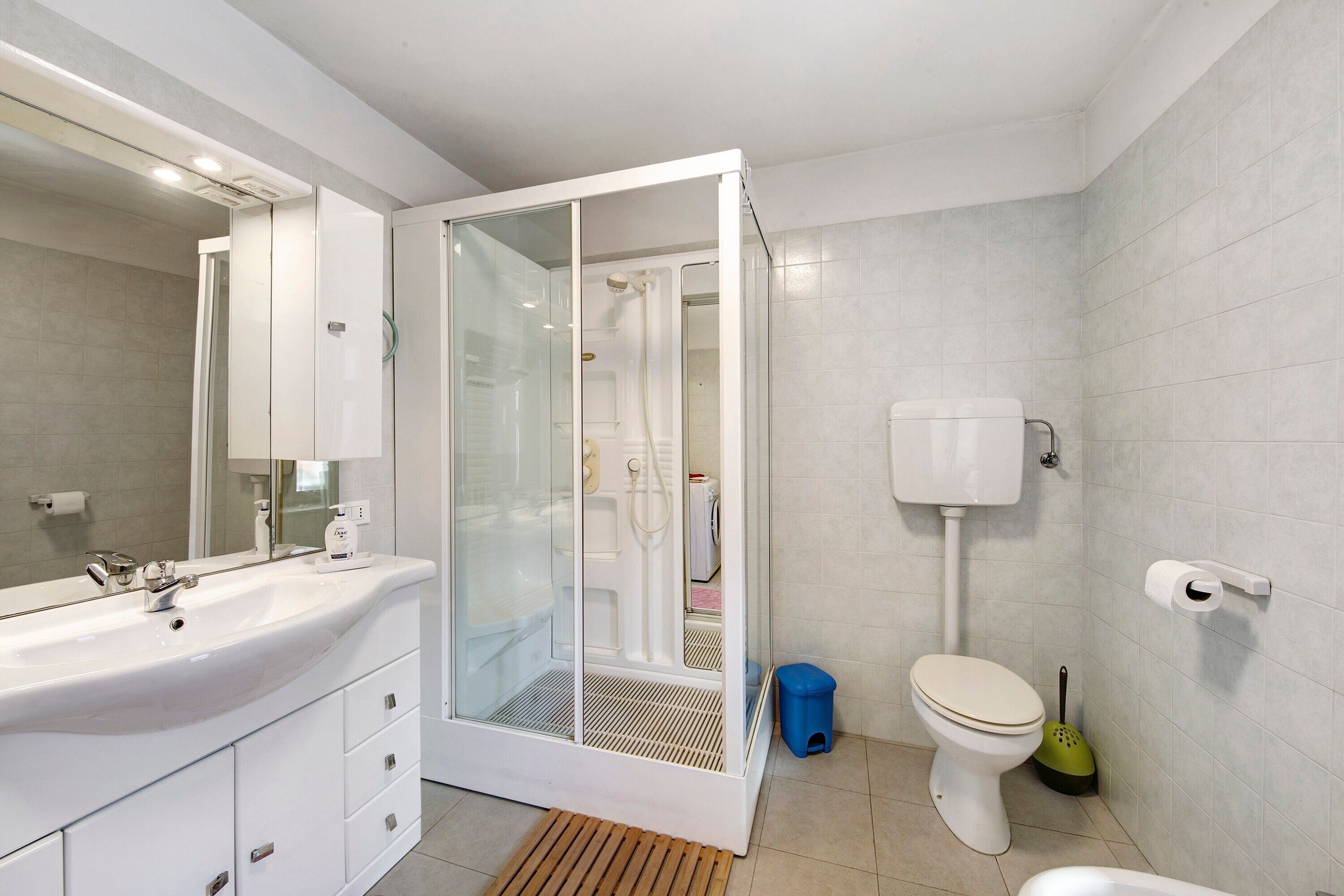 Un baño moderno con ducha envuelta en vidrio, un lavabo blanco y un inodoro.