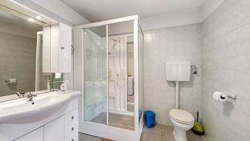 Un baño moderno con ducha envuelta en vidrio, un lavabo blanco y un inodoro.