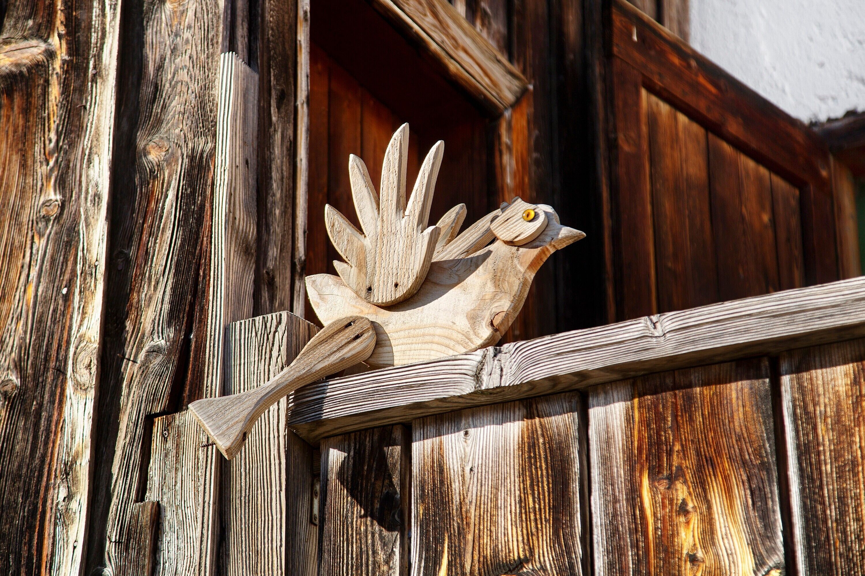 A rustic wooden door with a carved bird figure.