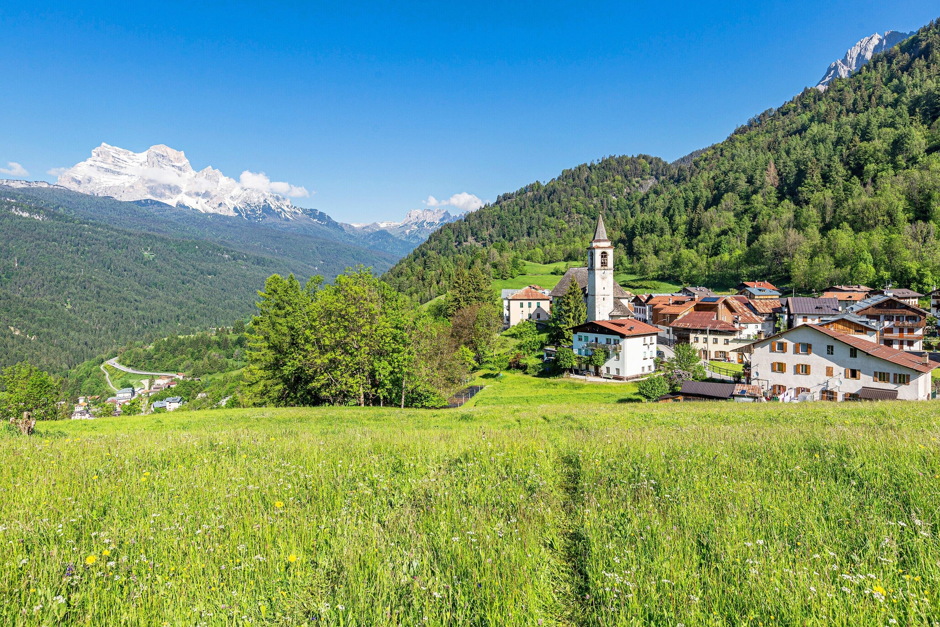 A village with a church, houses, and a mountain in the background.
