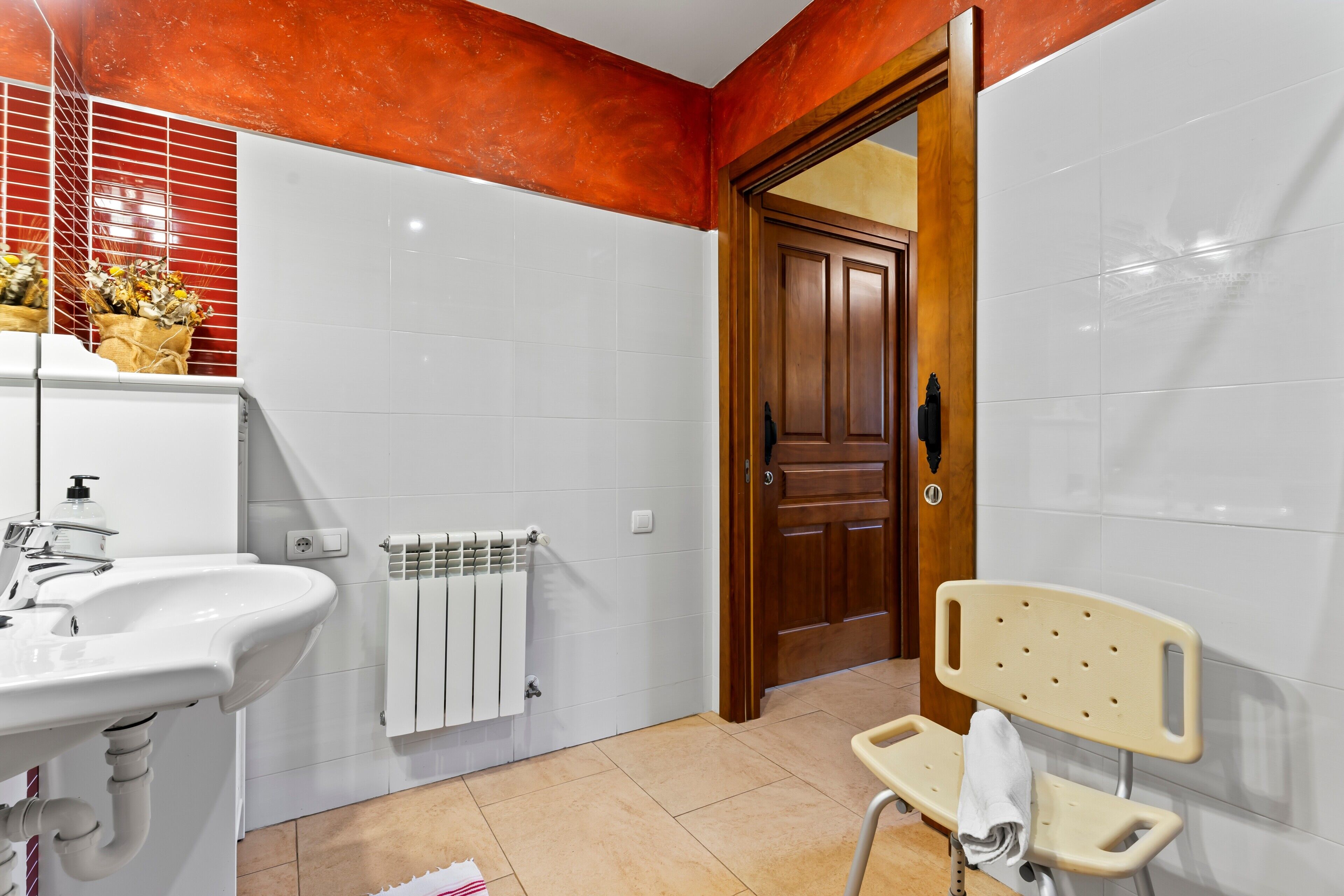 A bathroom with a sink, a towel rack, a radiator, and a wooden door.