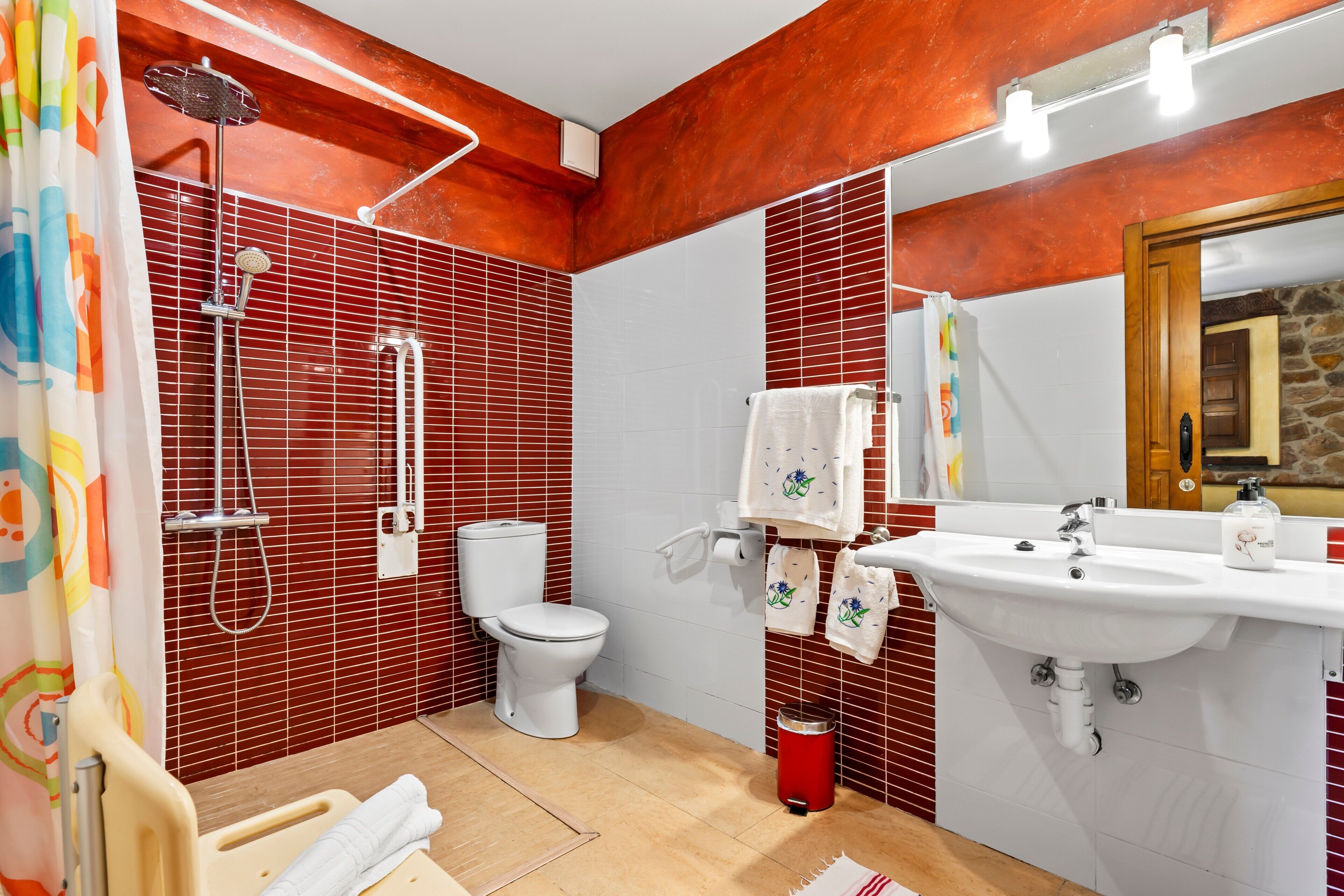 Ein Badezimmer mit Dusche, Toilette, Waschbecken und Spiegel.