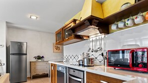A modern kitchen with stainless steel appliances, wooden cabinets, and a red microwave. - Apartment 'La Llosa' with Mountain Views, Private Terrace and Wi-Fi (Logrezana)