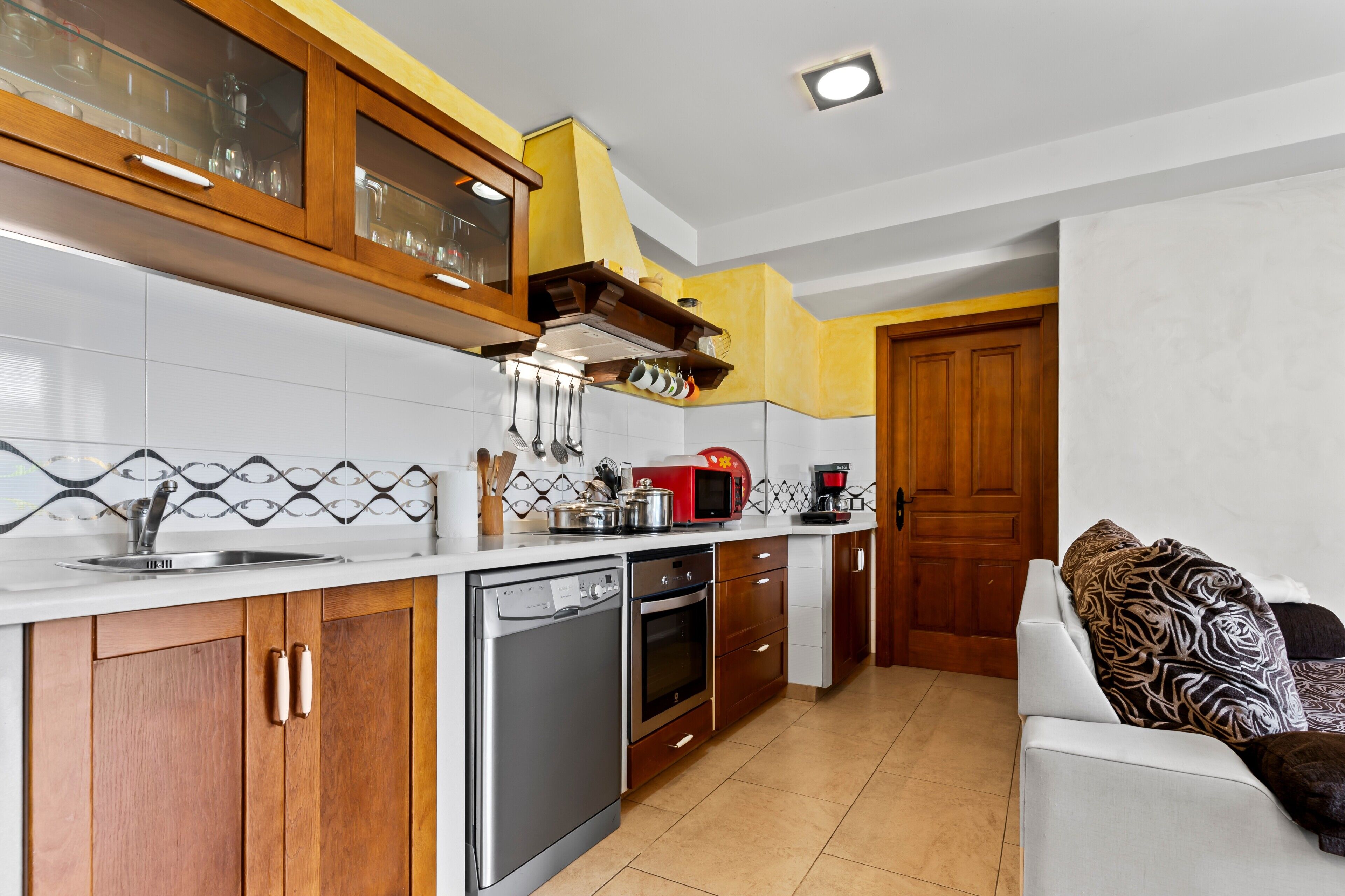 A compact kitchen with wooden cabinets, a dishwasher, an oven, and a microwave.