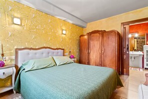 A bedroom with a bed, nightstand, dresser, and a bathroom with a sink and mirror. - Apartment 'La Llosa' with Mountain Views, Private Terrace and Wi-Fi (Logrezana)