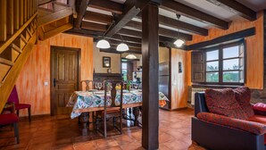 A rustic interior with a dining area, wooden staircase, and a sofa. - Pedregal Farmhouse with Shared Terrace, Private Garden, and Wi-Fi (Gijon)