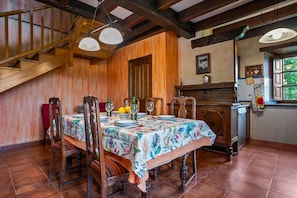 Uma sala de jantar com uma mesa de madeira, cadeiras e uma escada.