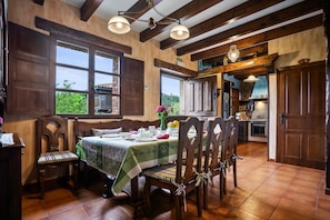 Un comedor con muebles de madera, una mesa preparada para cuatro personas y vistas al exterior.