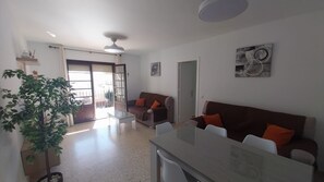 A living room with a sofa, a dining table, and a potted plant. - Apartment 'Chipiona Centro y Playa' with Private Terrace, Balcony and Wi-Fi (Chipiona)