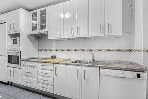 A modern kitchen with white cabinetry, a Bosch dishwasher, a microwave, and a double sink. - Apartment 'Chipiona Centro y Playa' with Private Terrace, Balcony and Wi-Fi (Chipiona)