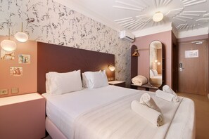 Een hotelkamer met een groot bed, nachtlampjes, een spiegel en een wandairconditioner.