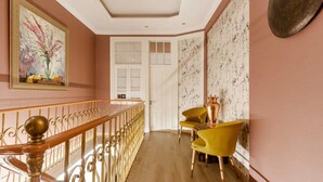 Un couloir avec un escalier, une porte et deux chaises jaunes.