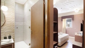 A modern bathroom with a shower, toilet, and sink. - Room 'Quarto Casal Comfort Plus 104' with Shared Terrace, Wi-Fi and Air Conditioning (Faro)
