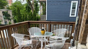 Una terraza de madera con mobiliario exterior, incluyendo sillas y una mesa.