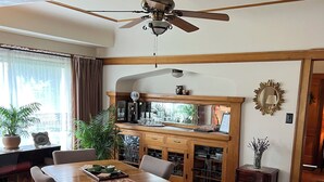 Un comedor con una mesa y sillas de madera, un ventilador de techo y una zona de cocina con armarios y una encimera.