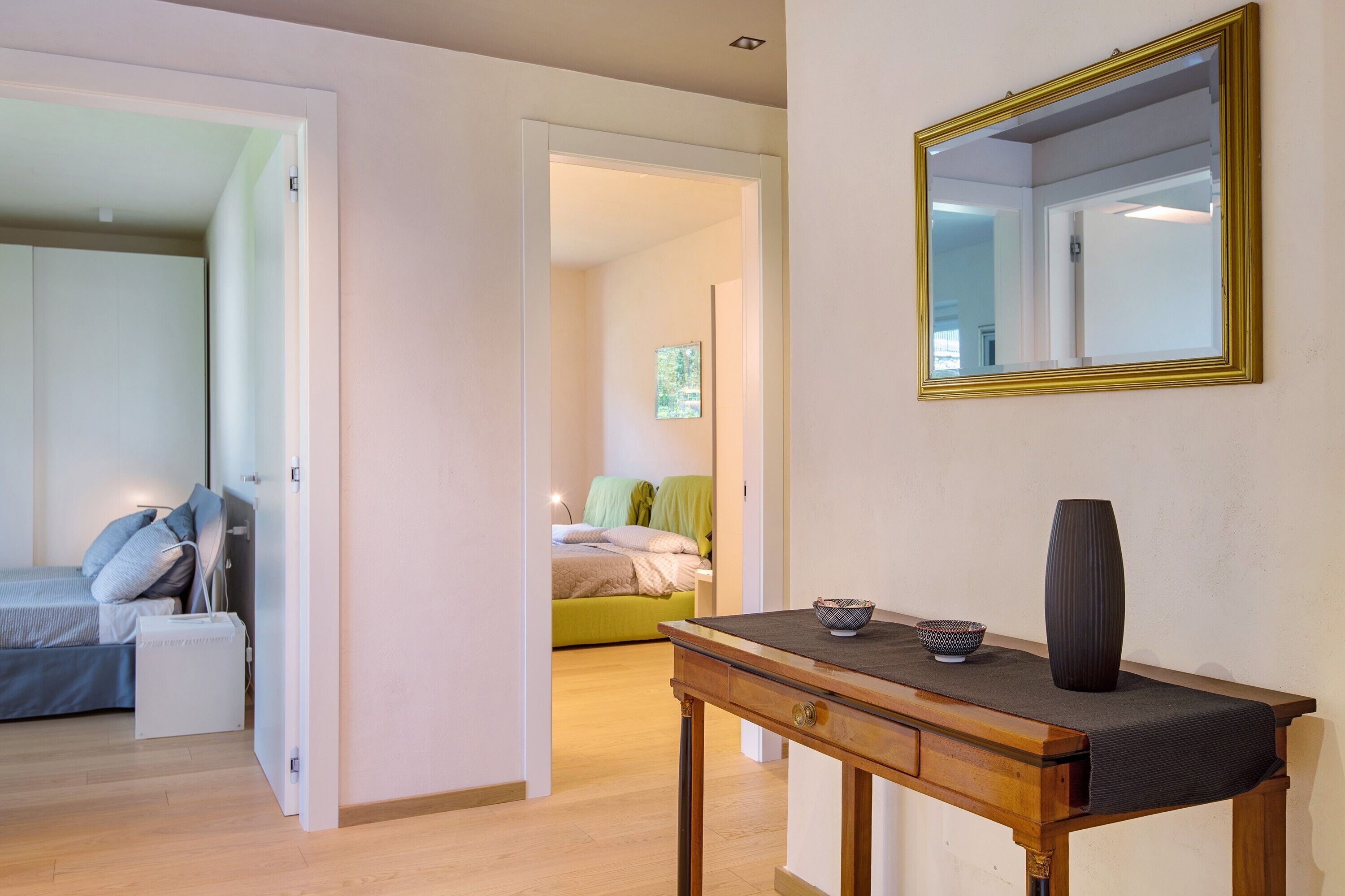A bedroom with a bed, bedside table, and a mirror.