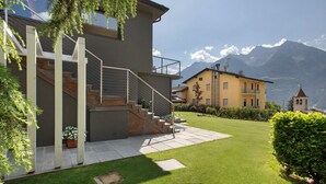 A modern house with a staircase, a well-maintained lawn, and a mountain view.