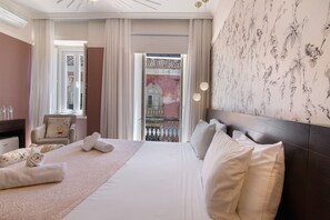 Une chambre d’hôtel avec un lit, une chaise, un bureau avec un ordinateur et une vue sur l’extérieur.