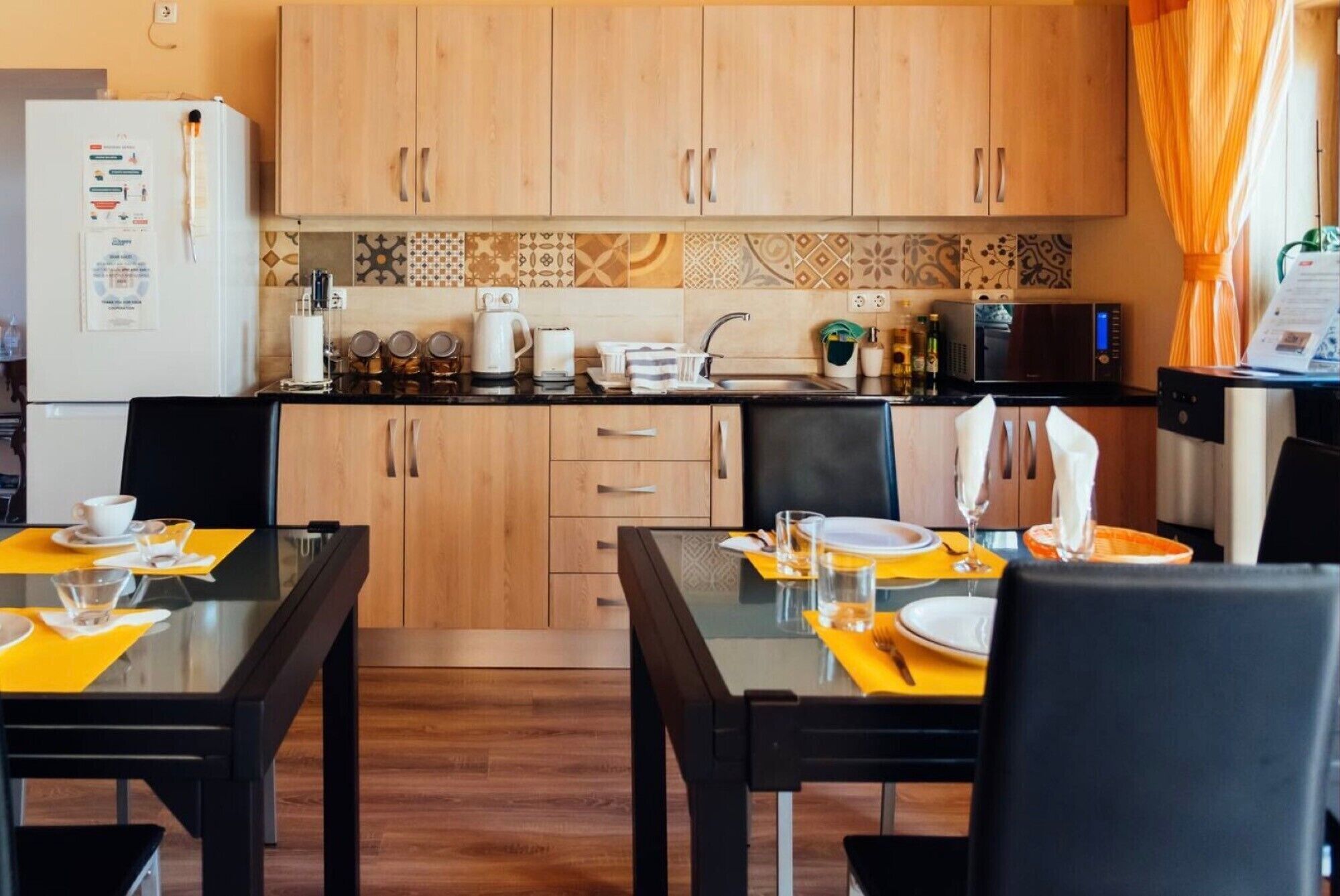 Une cuisine compacte dotée de meubles en bois, d’un réfrigérateur, d’un four à micro-ondes et d’un coin repas avec une table et des chaises.